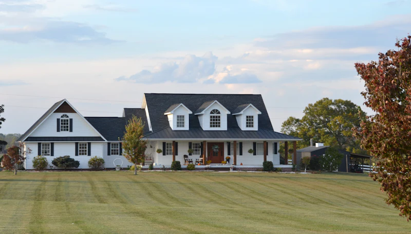 White home with dormer windows behind a wide green lawn