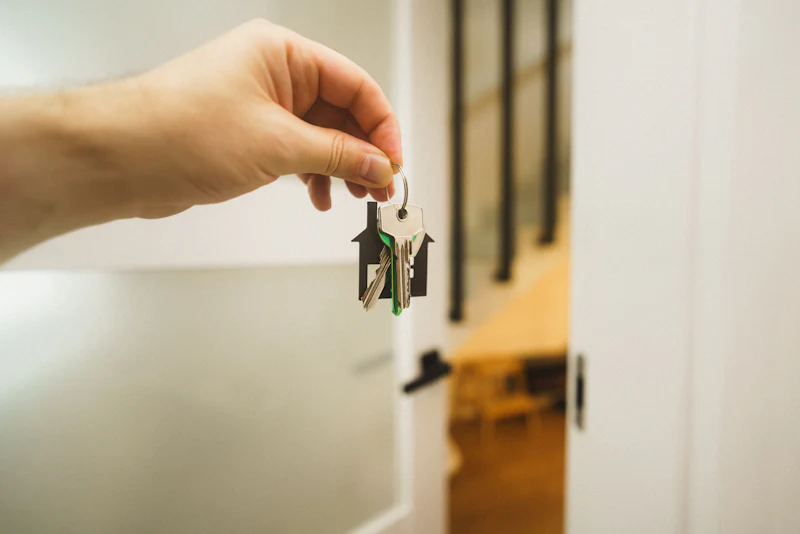 Hand holding a key up to an open front door