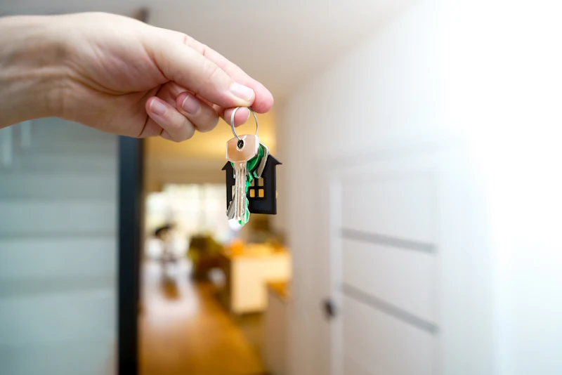 Hand holding house keys at an open front door