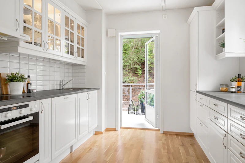 White kitchen with wood floors and an open back door