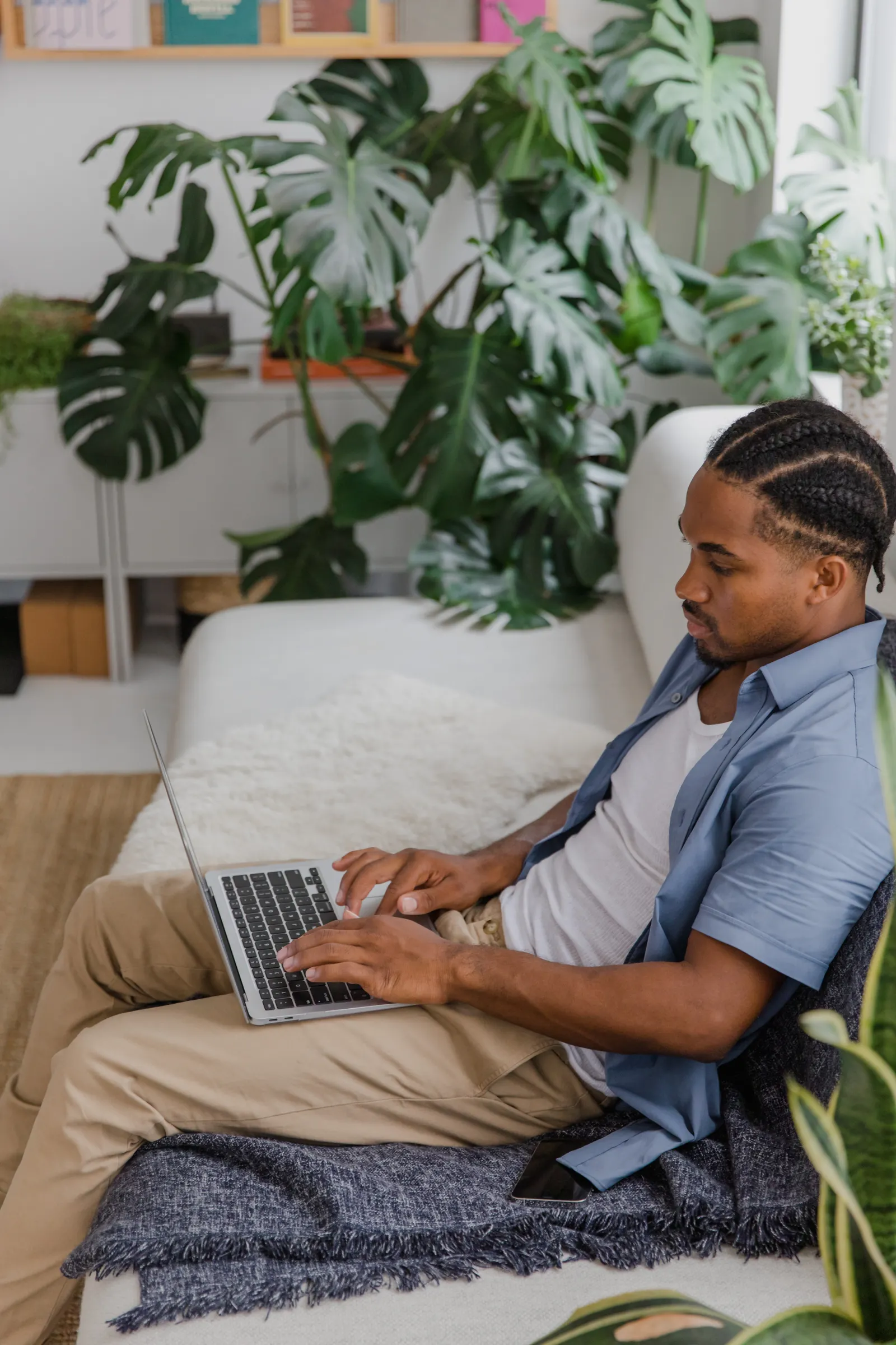 Man on a sofa browsing on a laptop in a bright living room