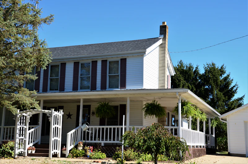 White farmhouse with a wrap-around front porch
